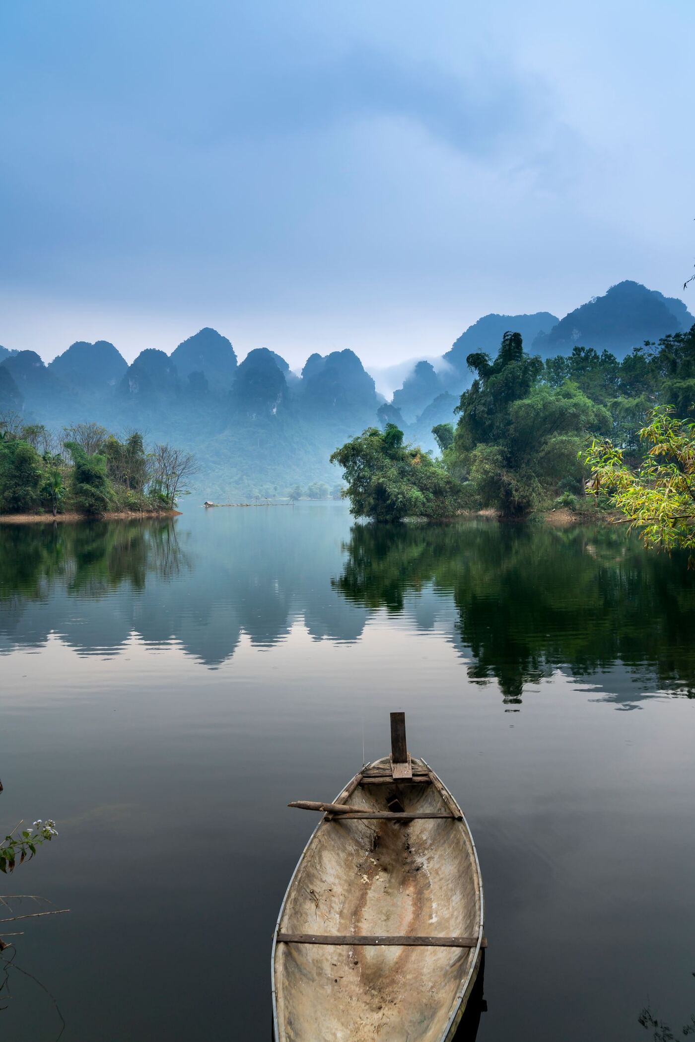 Thuyền gỗ trên mặt hồ lặng, núi đá vôi Ninh Bình