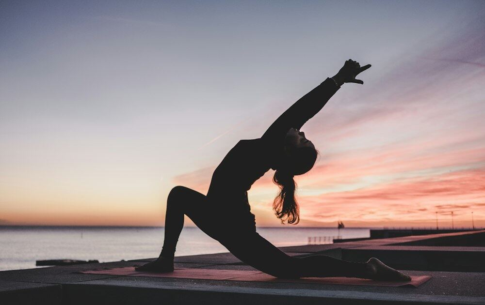 Người tập yoga trên bờ biển lúc hoàng hôn